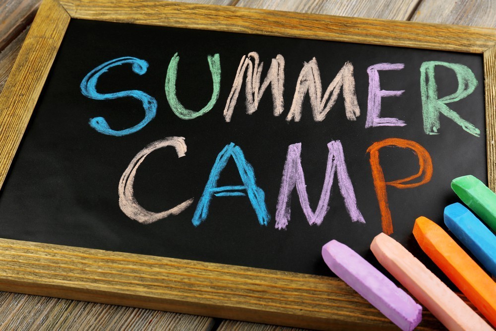 "Summer camp" in colorful chalk on a black background
